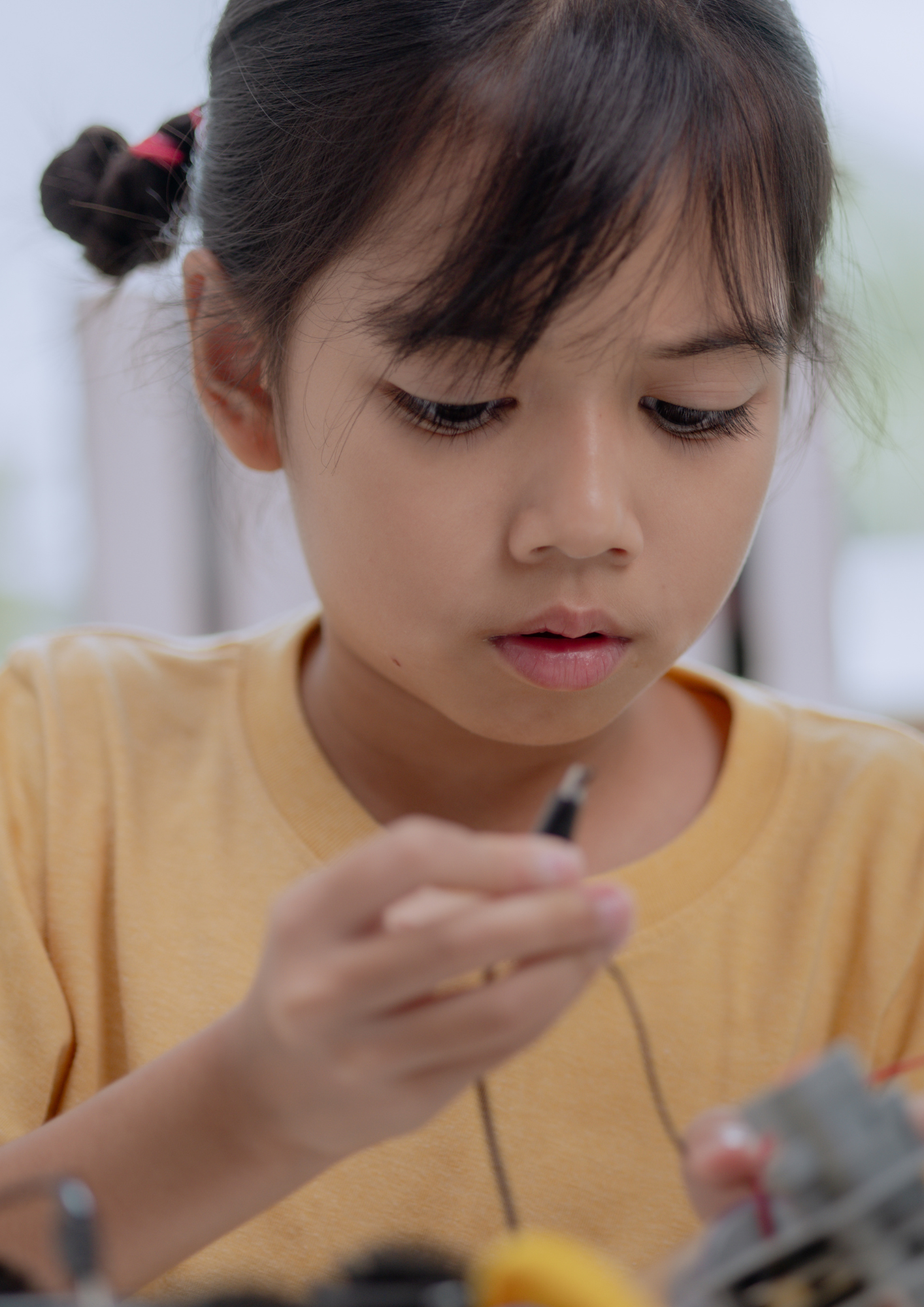 Child concentrating while connecting a component during a workshop.